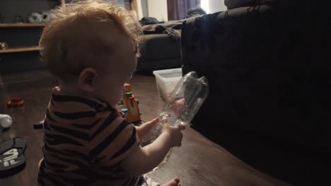 niña jugando con una botella de agua de plástico en la sala de estar
