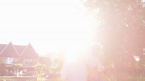 Grandmother-Playing-Game-And-Swinging-Granddaughter-Around-In-Garden-Of-Summer-Pub