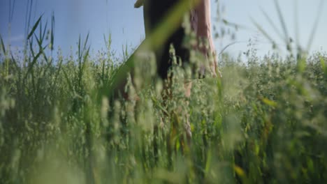 Woman-walking-in-field-with-her-hand-in-the-grass