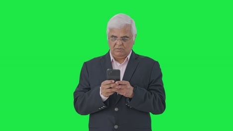 Angry-Indian-senior-manager-using-mobile-phone-Green-screen