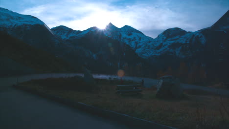 Calming-shot-of-tourist-taking-a-picture-in-the-distance-in-back-drop-of-massive-mountain-range-landscape-at-dusk-in-Austria,-wide-view