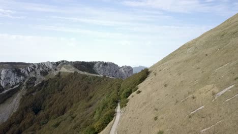 Soaring-backwards-over-steep-grasslands-in-France,-Parc-naturel-régional-du-Vercors