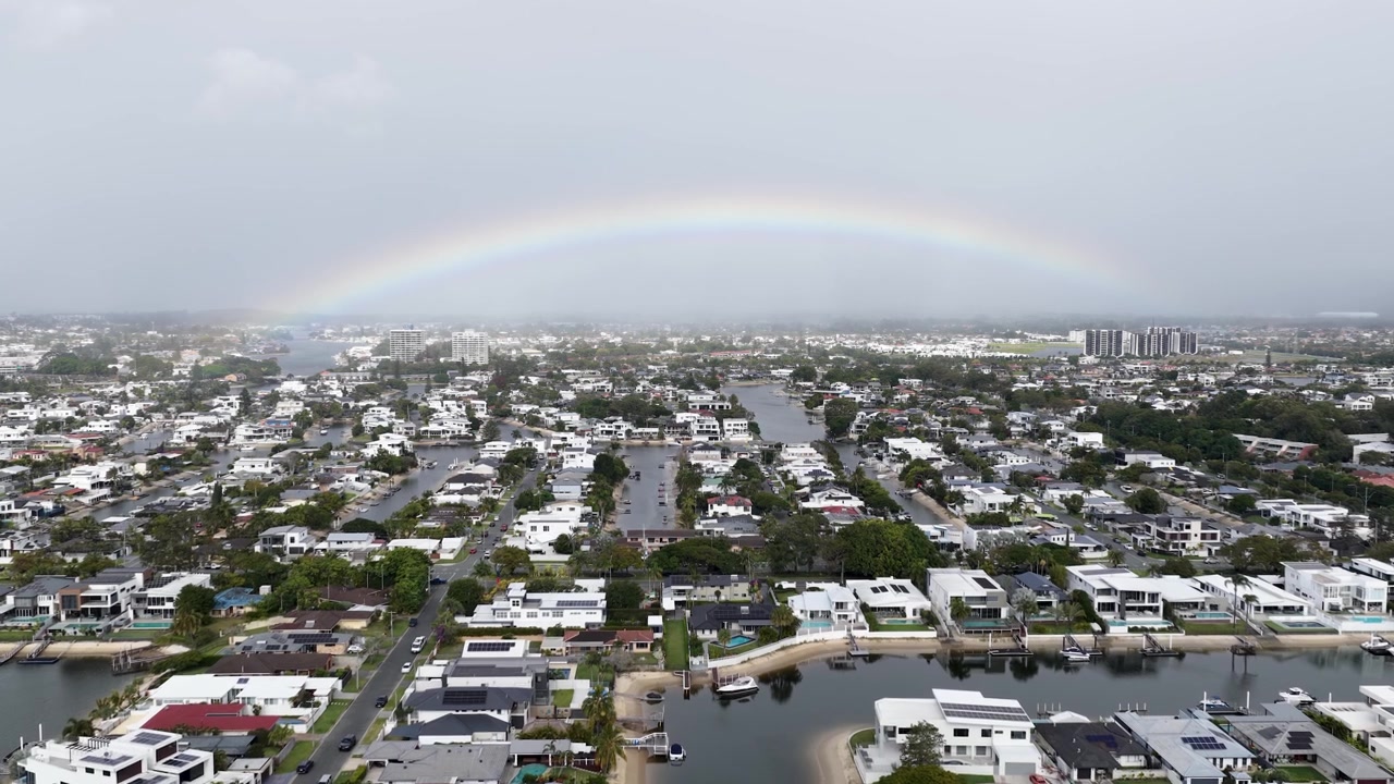 Vista aérea de un arcoíris sobre un barrio residencial frente al mar