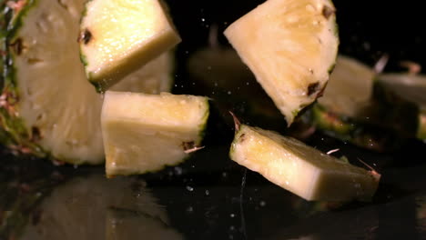 trozos de piña cayendo sobre un fondo negro