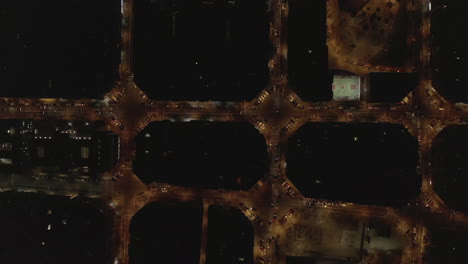 Top-down-ascending-footage-of-traffic-in-streets-at-night.-Vehicles-passing-through-intersections.-Barcelona,-Spain