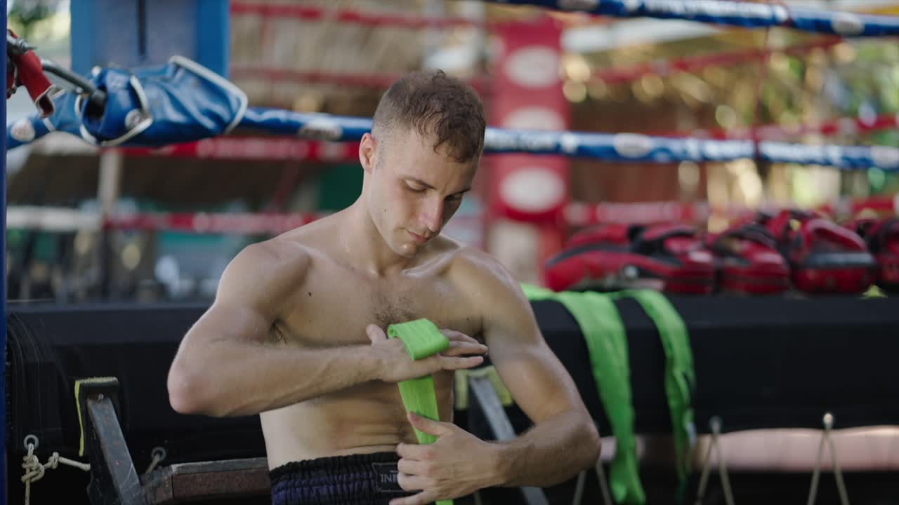 A man wrapping his hands in a boxing ring, preparing for a fight or training