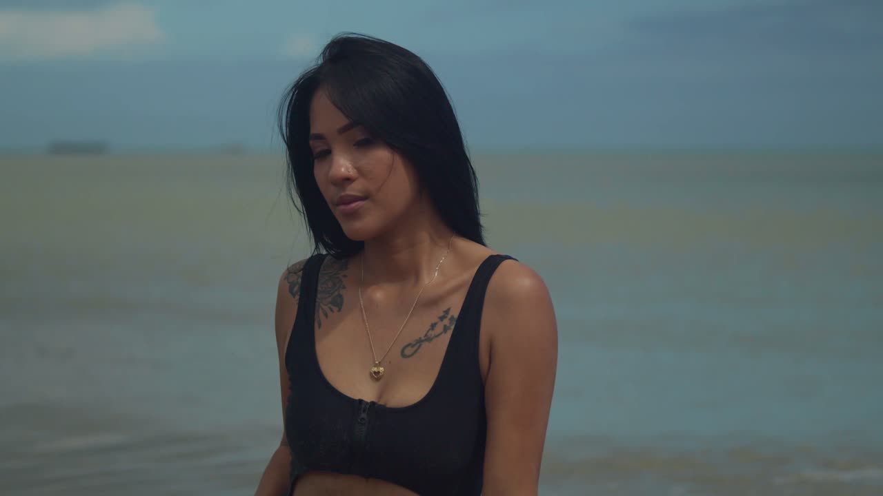 은 날에 에 고, 긴 자연 머리카락을 가진 히스패닉 소녀는 바다의 파도가 배경으로 비키니를 입고 열대 카리브 해변을 즐기고 있습니다.