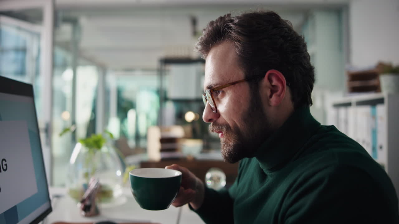 hombre bebiendo café mientras trabaja en la computadora