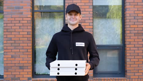 young man holding pizza boxes