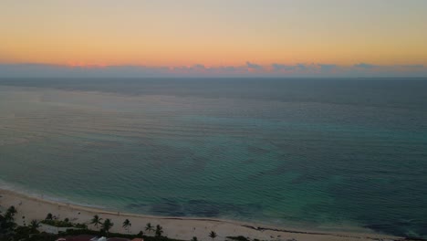 aerial view of the tropical ocean pulling away to reveal the land of mexico's coast during golden hour