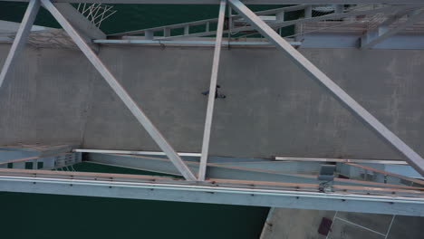 vista aérea de pájaro sobre un peatón solitario caminando por el puente del puerto
