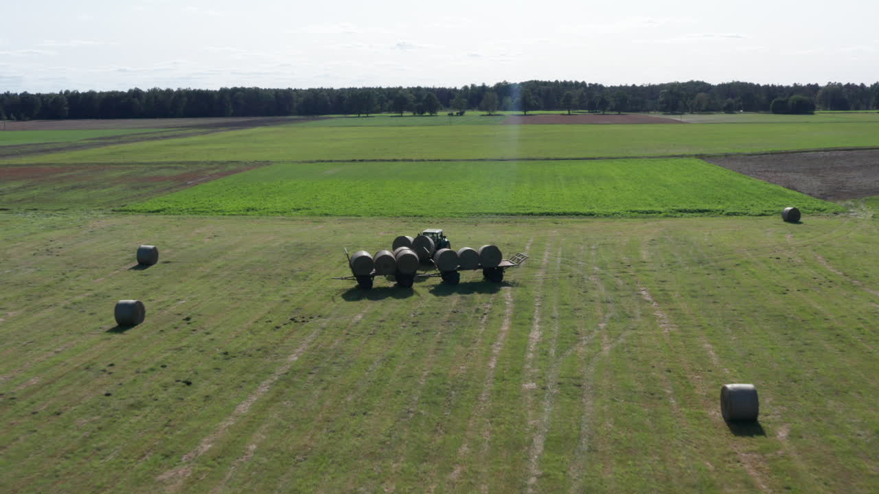 건초더미가 쌓인 마차에 두 개의 큰 짚이나 건초더미를 싣고 있는 트랙터의 공중 발사