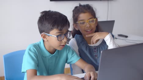 pareja de escolares con gafas trabajando en una tarea