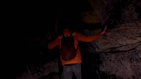 male hiker exploring a dark cave 4k