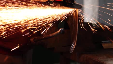 craftsman grinding metal with grinder in vice