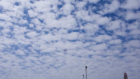 low angle view of single-engine airplane crossing the blue sky with fluffy clouds, over the city