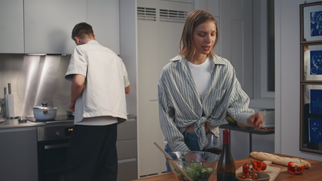 Une femme heureuse savoure son vin en cuisinant avec son mari. Une famille joyeuse trinque.