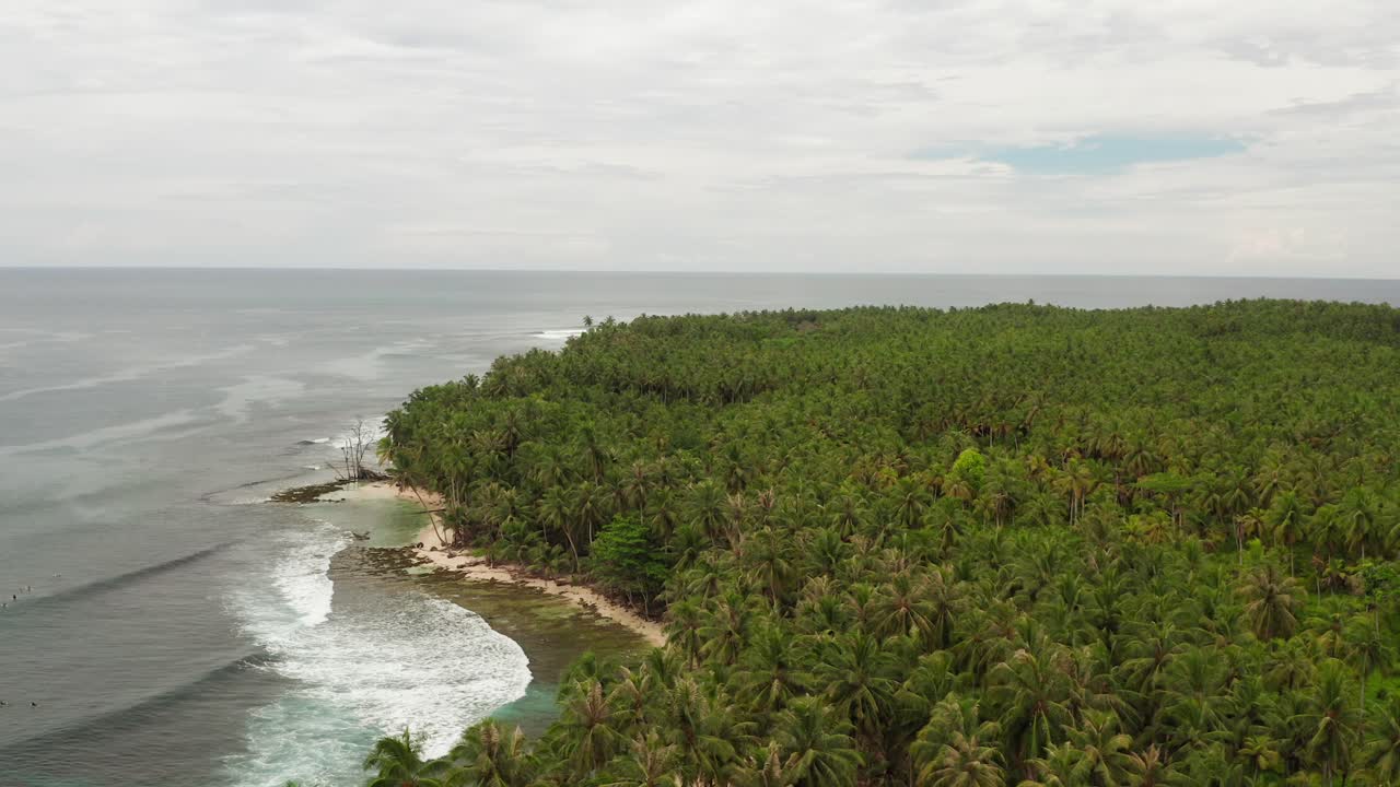 toma aérea de paralaje de surfistas flotando en la bahía de palm beach en indonesia