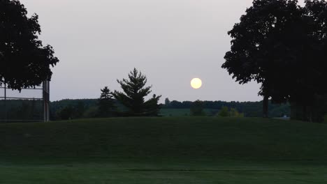 large setting sun over grassy hill in park - burlington ontario canada