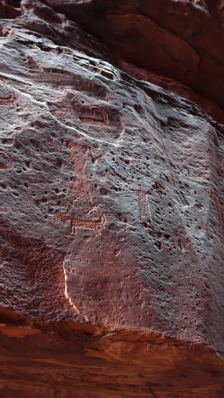 Panoramica ravvicinata su incisioni e iscrizioni preistoriche incise nella parete rocciosa del deserto.