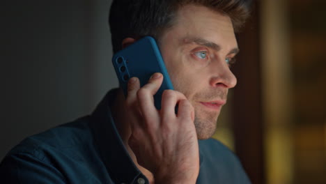 Talking man enjoy call looking distance evening apartment closeup. Guy speaking