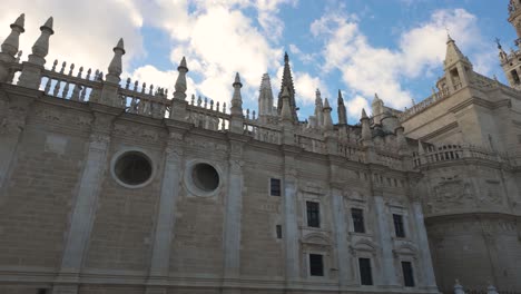 ornate spires and stonework of seville cathedral against a partly cloudy sky