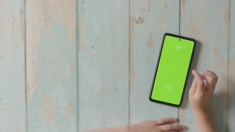 Overhead-Studio-Shot-Of-Child-Using-Green-Screen-Mobile-Phone-1