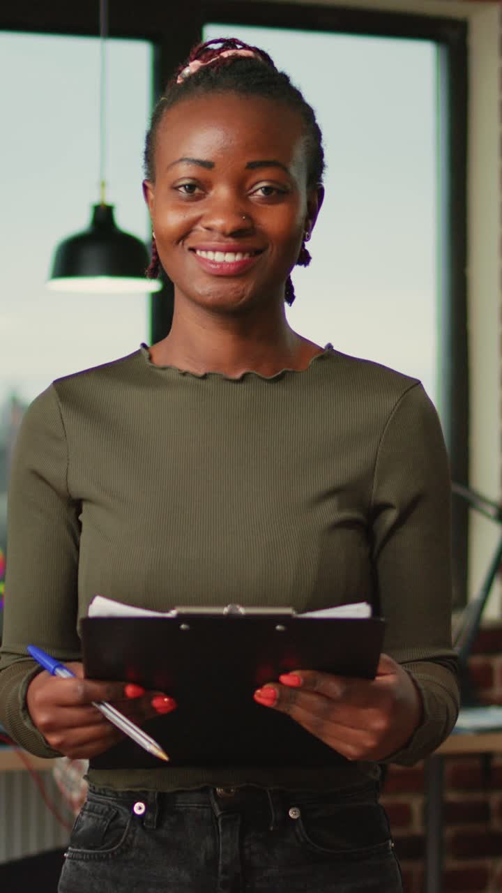 Vertical video: African american female employee reading documentation work