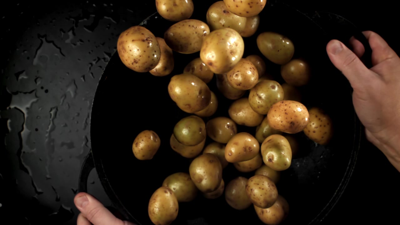 Patate fresche e crude che saltano in una padella nera, al rallentatore