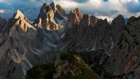 jagged peaks of dolomites, man stands alone on cliff, italy