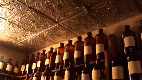 collection of vintage amber glass bottles on shelves with decorative ceiling