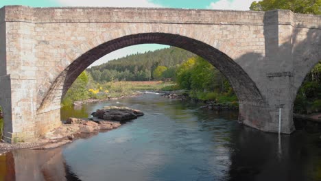 arcos de puente de piedra sobre el río highland que fluye en escocia, drone