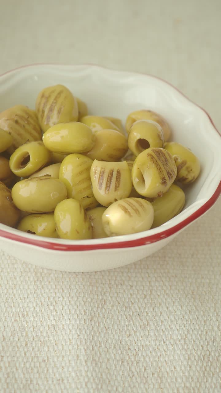 Primo piano di olive verdi grigliate in una ciotola bianca.