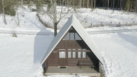 Rising-Aerial-Shot-Of-Ski-Lodge-In-Winter-Mountain-Landscape,-Wood-Log-Cabin-Hut