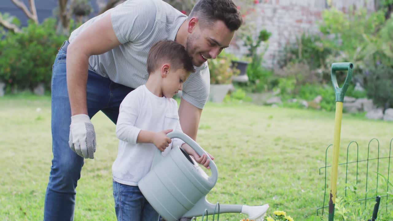 padre y hijo caucásicos felices jardinería y riego de plantas juntos