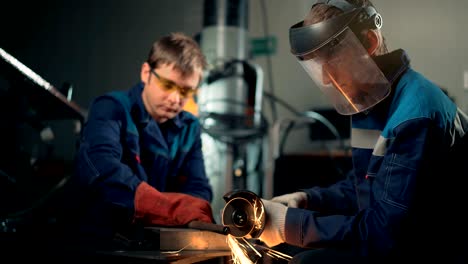 workers wearing mask cuts metal with hand disc grinder abrasive saw