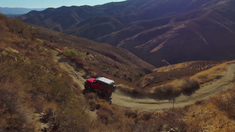 Red-jeep-offroad,-driving-outdoor-in-California-desert-hills,-aerial-drone-view