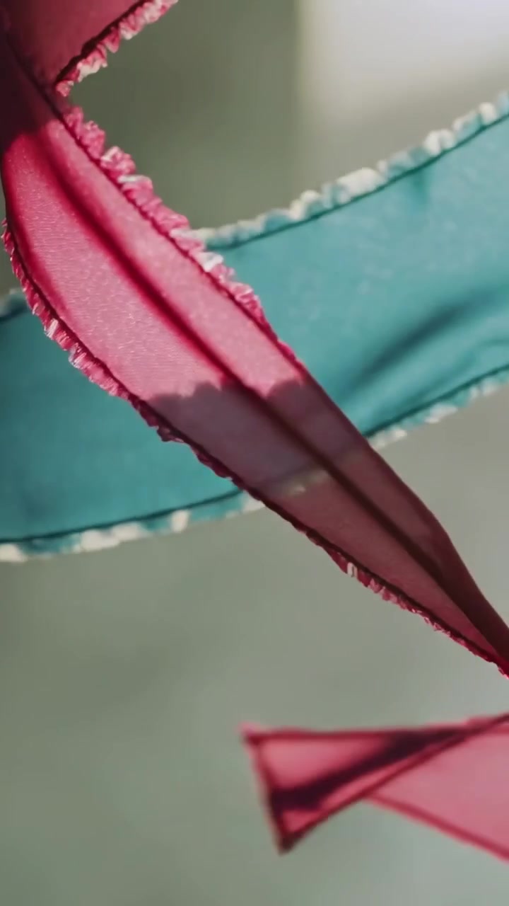 Vertical video: Camera moving, sheer cyan magenta ribbons shifting near yellow lamp, showing edges