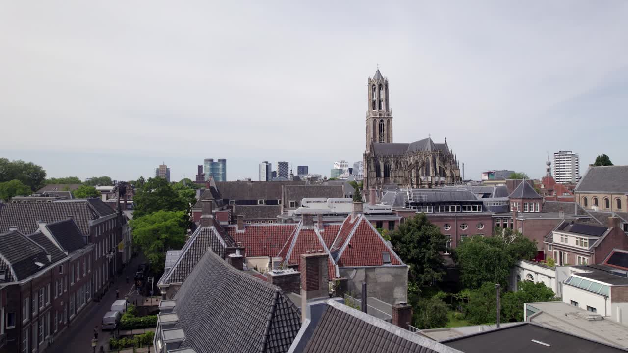 Rooftops of city center with De Dom church tower and the gothic architecture of the Utrecht diocese rising above. Holland religious tourist destination with modern buildings in the background.