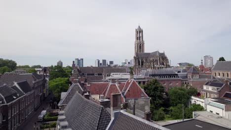 rooftops of city center with de dom church tower and the gothic architecture of the utrecht diocese rising above. holland religious tourist destination with modern buildings in the background.