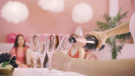 side view of woman's hands pouring champagne in crystal glasses on the table