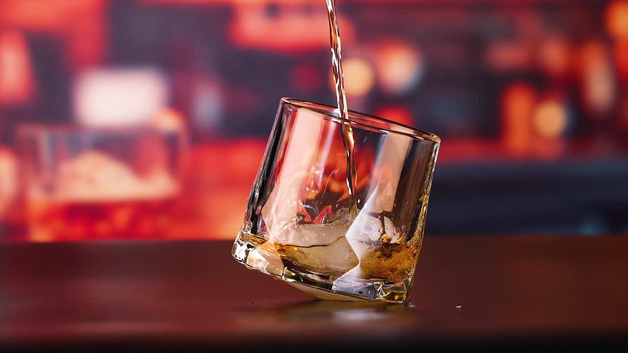 whisky vertiendo en un vaso con hielo