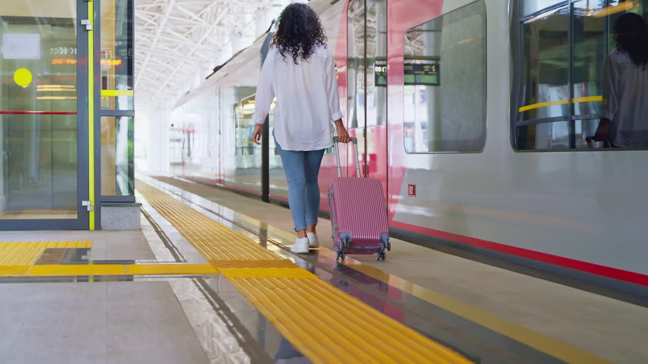 mujer caminando con una maleta en la estación de tren