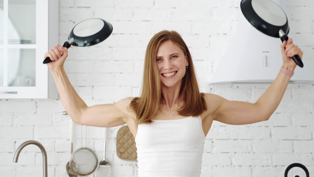 Girl with two pans in the kitchen shows different emotions