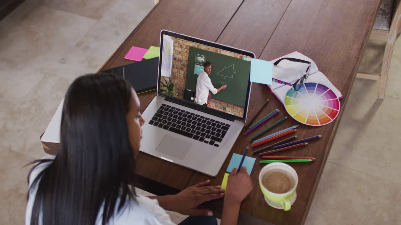 estudiante caucásica usando la computadora en videollamada con un profesor masculino, escribiendo