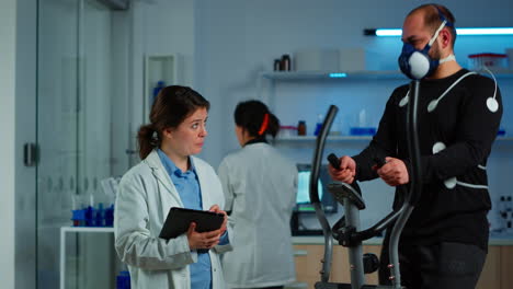 investigador médico hablando con un deportista mientras mide su resistencia