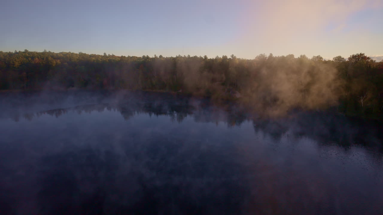 Cinematic overhead view of mist floating above the water at dawn