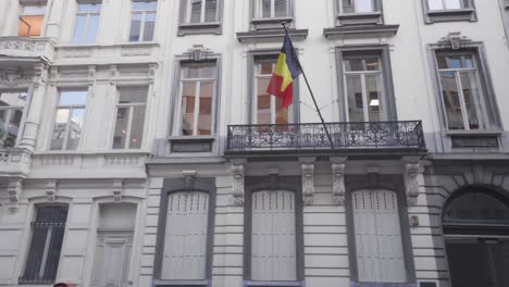 belgian flag flying on a balcony in brussels, belgium, low angle wide shot