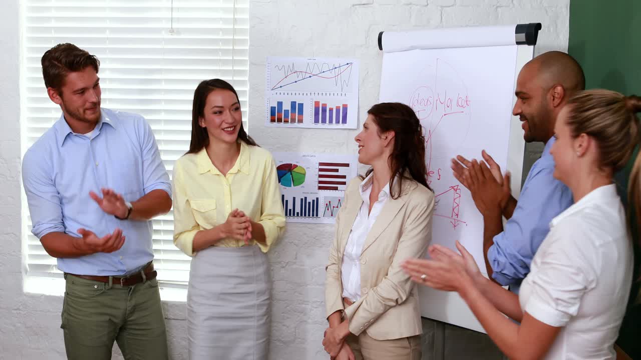 un equipo de negocios casual aplaudiendo a su colega.