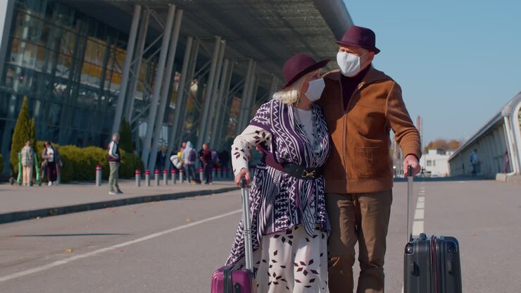 Turisti anziani pensionati, nonna e nonno, che camminano dall'aeroporto con i bagagli, coronavirus.